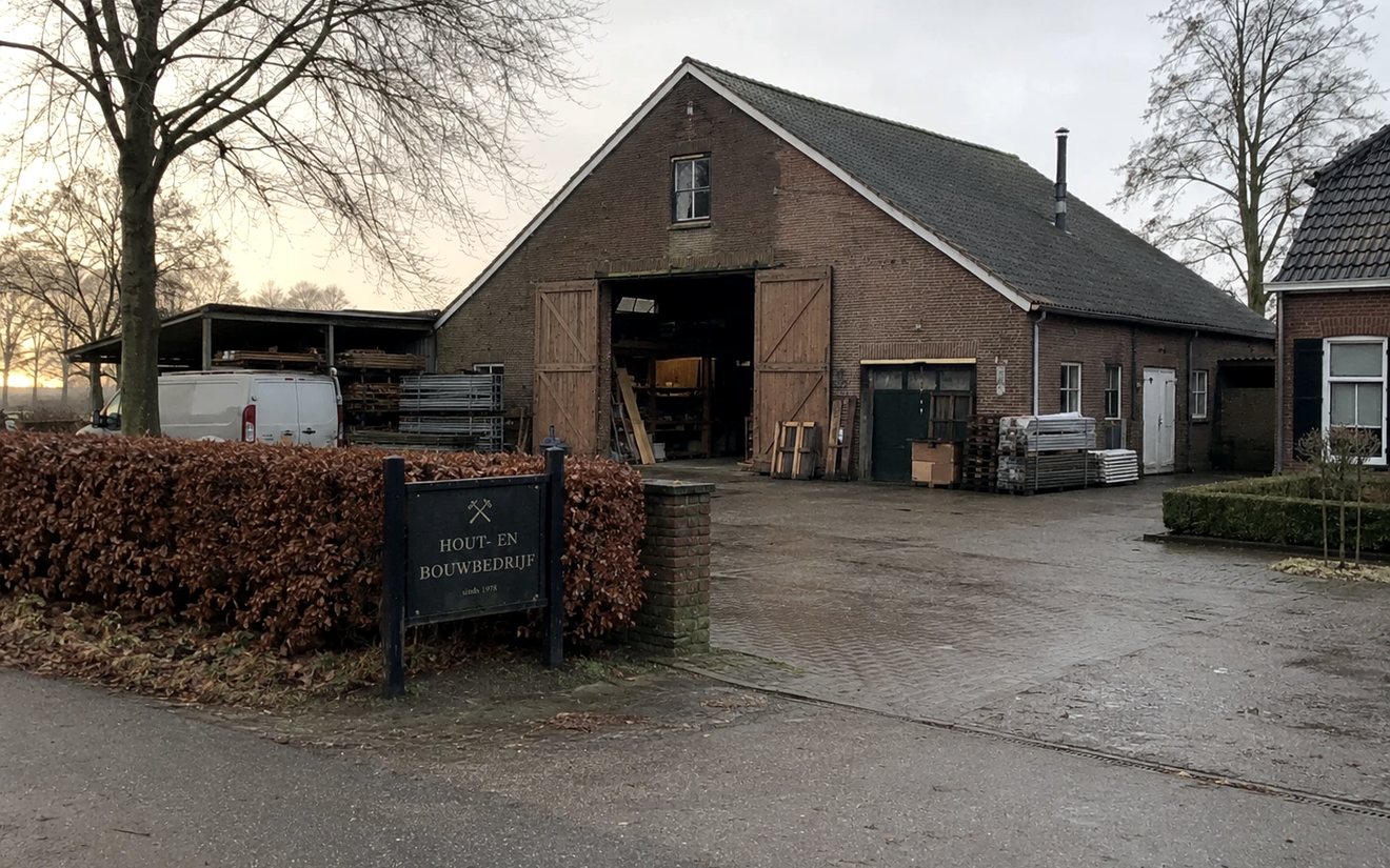 Ouder familiebedrijf met houten schuurdeuren, busje op het erf